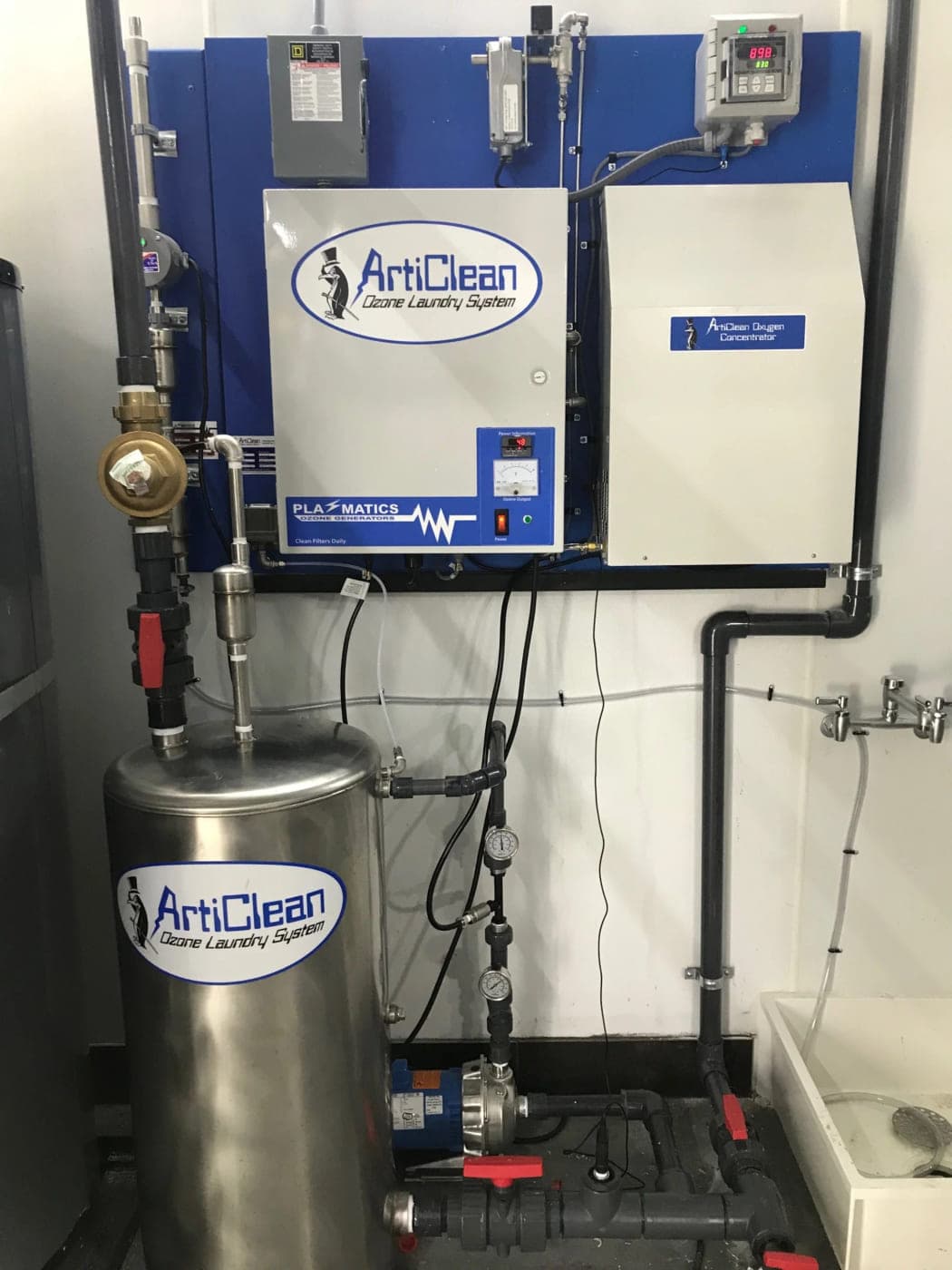 Stainless steel ozone contact tank plumbed into an ozone generator and control cabinet in a laundry room
