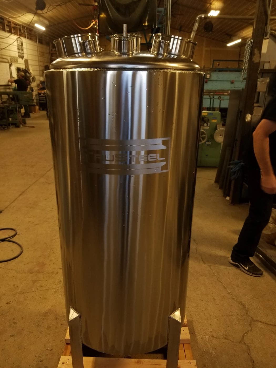 Polished vertical stainless steel vessel with three large ferrule ports on the domed top head