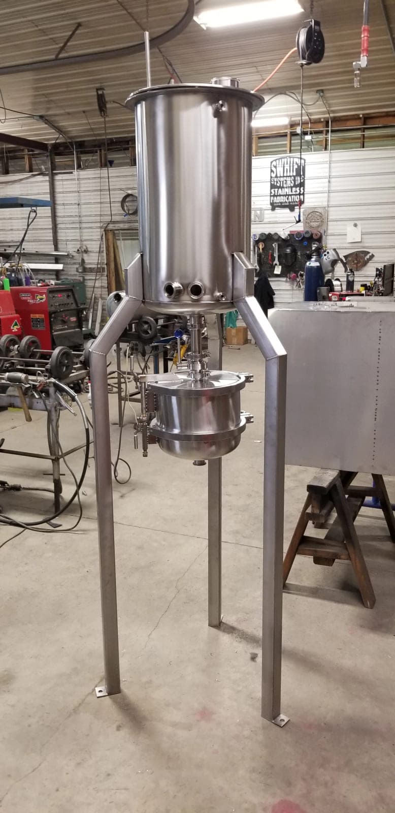 Stainless steel extractor vessel on tall legs above a clamped collection vessel